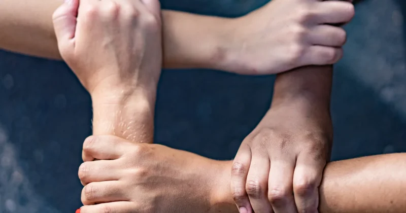 Four people interlocking hands