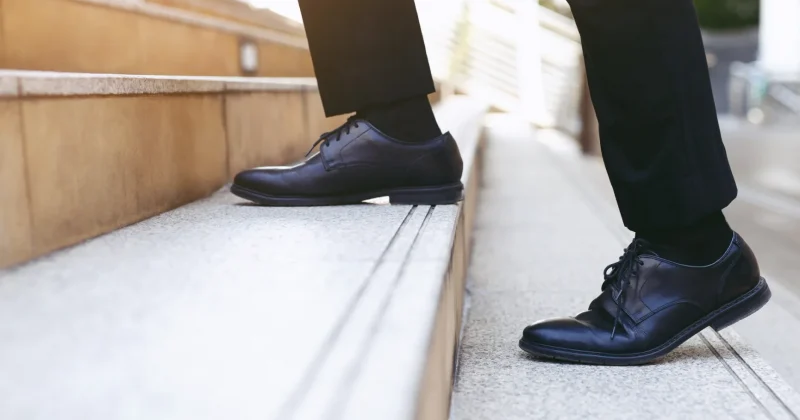 Man in business shoes taking first step on stairs