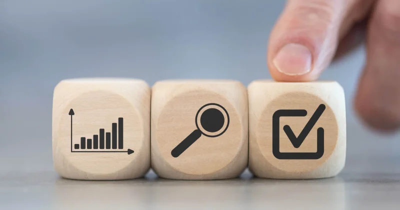 three wooden blocks with finger pointing to one with checkmark